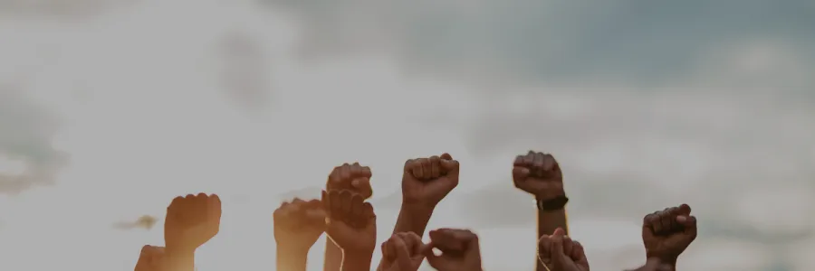fists raised together with sky in background